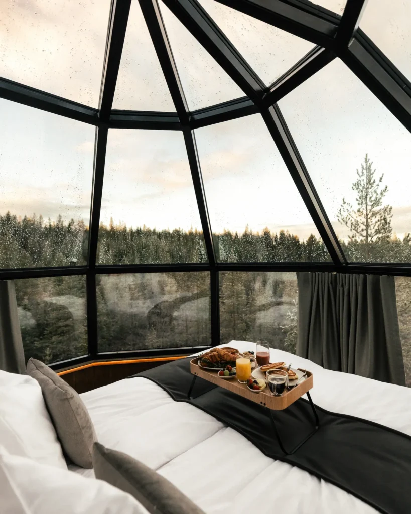 Breakfast in bed inside a luxury glass roof lodge with forest views in Lapland