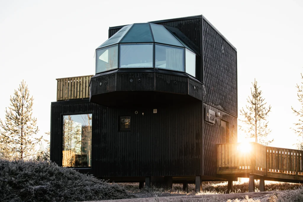 Modern two-story glass igloo villa glowing in the crisp Arctic morning sun.