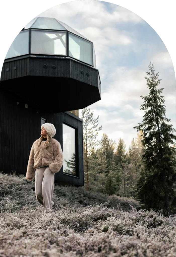 Guest walking through frost-covered heather beside a luxury modern cabin.