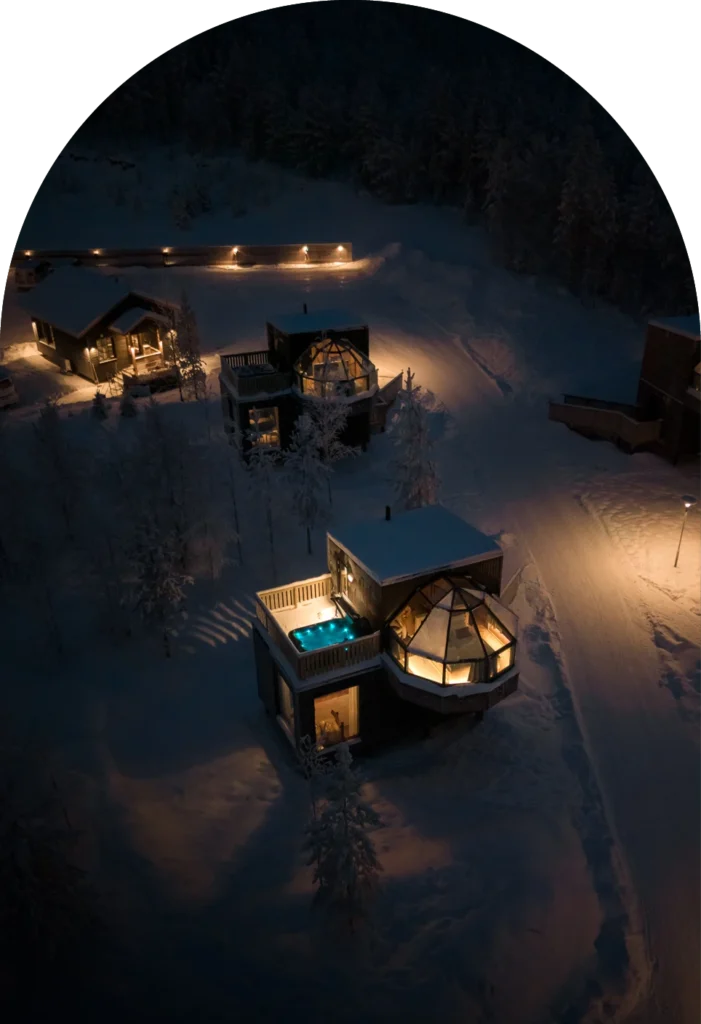 Aerial night view of two-story glass igloo with private rooftop hot tub.