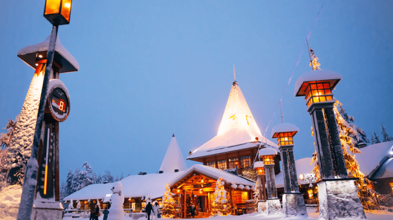 Santa Claus Village illuminated under twilight snow in Rovaniemi, Lapland.